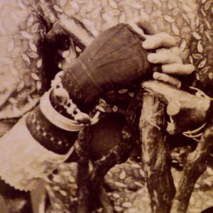 Könnte beinhalten: Nahaufnahme von Händen einer Person, die mehrere Armbänder und einen Handschuh trägt und einen Gehstock aus Holz hält. Die Person trägt ein Kleidungsstück aus gemustertem Stoff.
