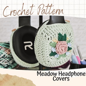 以下が含まれることがあります： Meadowヘッドフォンカバーのクロシェパターン。パターンは、ピンクとグリーンの花柄のグリーンのクロシェヘッドフォンカバーを特徴としています。