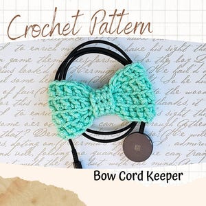 May include: A mint green crochet bow cord keeper. The bow is centered on a black cord, with a small, round, gray object at the bottom. The words "Crochet Pattern" and "Bow Cord Keeper" are written on the background.