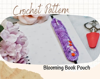 May include: A purple crocheted book pouch with embroidered flowers in orange and pink. The pouch is lying on a white notebook with the text "Blooming Book Pouch".