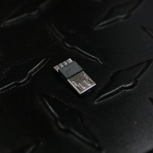 May include: A close-up of a small black USB connector with silver contacts.