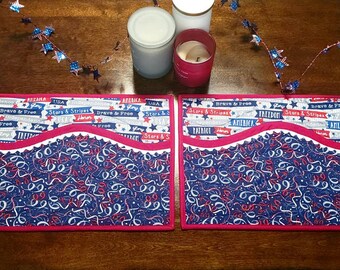 Peut inclure: Deux sets de table en tissu rouge, blanc et bleu avec un bord festonné et une poche de chaque côté. Les sets de table présentent un motif de rubans et d'étoiles rouges, blancs et bleus. Les sets de table portent les mots "Stars & Stripes", "Brave & Free", "America", "Freedom", et "Patriot" imprimés dessus.