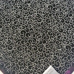 Puede incluir: Tela negra y blanca con un patr&oacute;n de espiral. La tela tiene un borde morado, verde y negro. Una etiqueta plateada con el texto "LIGHT SIDE CREATIONS" y un icono de m&aacute;quina de coser est&aacute; unida a la tela.