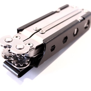 Könnte beinhalten: Ein schwarzes Multitool mit silberner Klinge und Zahnrädern. Das Werkzeug ist geschlossen und hat einen schwarzen Gürtelclip.