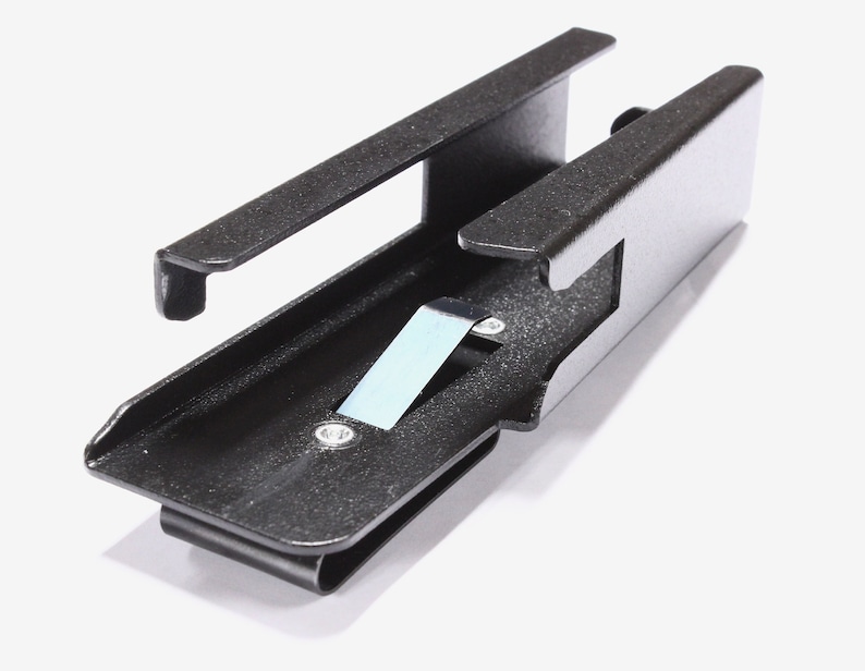 May include: A black metal clip with a rectangular body and a curved bottom. The clip has a small, light blue piece of metal attached to it. The clip is designed to hold items.