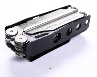 May include: A multi-tool with a black handle and silver tools. The text "WAVE" is visible on one of the tools. The tool has a black clip and several hexagonal cutouts on the side.