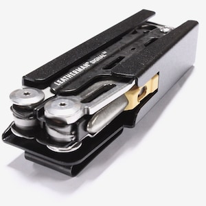 May include: A black and silver multi-tool with the text "LEATHERMAN SIGNAL" visible. The tool has a clip and several visible components, including a blade and other tools. The multi-tool is designed for outdoor use and survival.