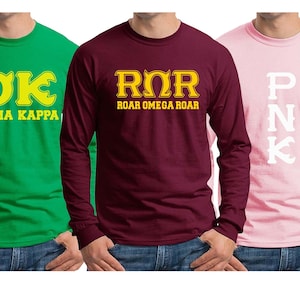 May include: Three long-sleeved t-shirts with different fraternity logos. The first shirt is green with a yellow "OK" logo and the text "OOZMA KAPPA". The second shirt is maroon with a yellow "RΩR" logo and the text "ROAR OMEGA ROAR". The third shirt is pink with a white "PNK" logo.