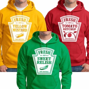 May include: Three hooded sweatshirts in yellow, red, and green. Each features a white label design with the word "FRESH" and a food product name: "YELLOW MUSTARD", "TOMATO KETCHUP", and "SWEET RELISH". The sweatshirts have a front pocket and a drawstring hood.