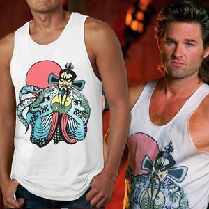 May include: White tank top with a colorful graphic print of a cartoon character with a red sun behind it. The character is wearing a green and blue robe and holding a yin yang symbol.