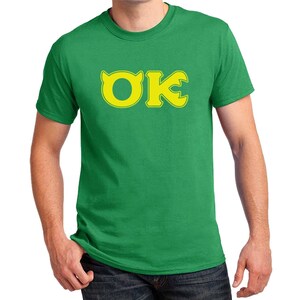 May include: A green t-shirt with a yellow "OK" logo. The "O" has a small horn on top.