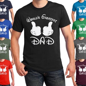 Peut inclure: Un t-shirt noir avec du texte blanc qui dit "World's Greatest Dad" et deux mains blanches de Mickey Mouse faisant un pouce en l'air. Le t-shirt est disponible en dix couleurs diff&eacute;rentes.