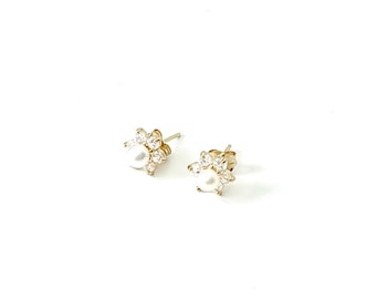 May include: A pair of gold stud earrings with a pearl centre and a halo of small clear stones.