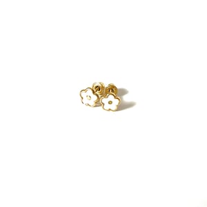 May include: A pair of gold flower-shaped stud earrings with white enamel.