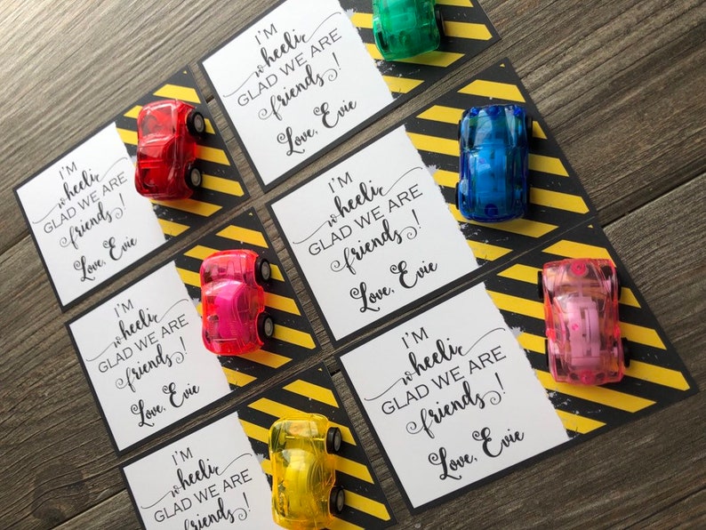 May include: Six small cards with a black and yellow striped background. Each card has a small toy car on it and the text "I'm wheelic GLAD WE ARE friends! Love, Evie".