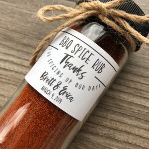 May include: A small glass jar filled with red BBQ spice rub, tied with twine and a label that reads "BBQ Spice Rub" and "Thanks for spicing up our day! Brett & Erica March 9, 2019".