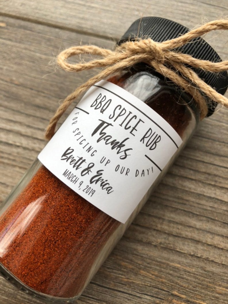 May include: A small glass jar filled with red BBQ spice rub, tied with twine and a label that reads "BBQ Spice Rub" and "Thanks for spicing up our day! Brett & Erica March 9, 2019".
