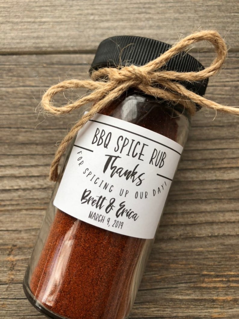 May include: A small glass jar filled with brown BBQ spice rub, tied with twine and a label that reads "BBQ Spice Rub" and "Thanks for spicing up our day! Brett & Erica March 9, 2019".