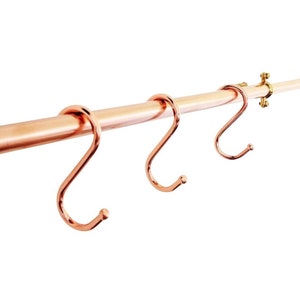 Three S-hooks on a copper rail serve as a utensil rack for hanging various items.