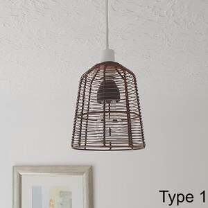 A bronze metal cage retro pendant hanging light shade, with a braided cord, suspended in a room, providing a warm, vintage glow.