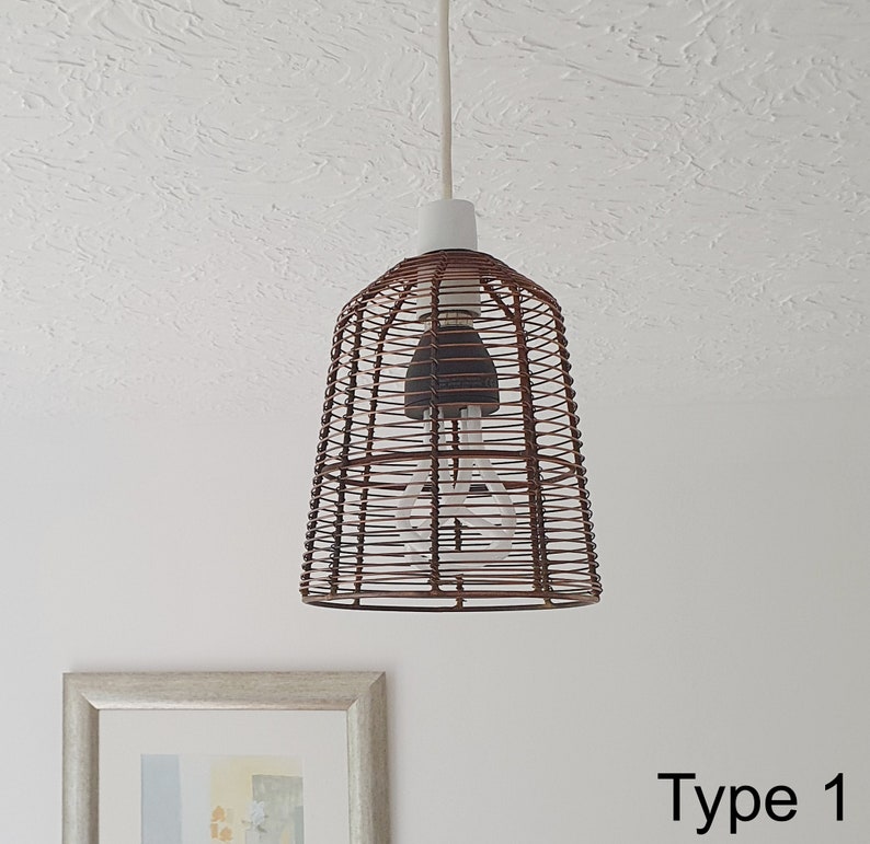 A bronze metal cage retro pendant hanging light shade, with a braided cord, suspended in a room, providing a warm, vintage glow.
