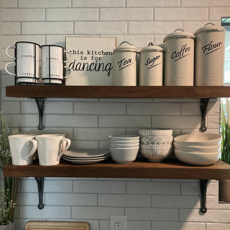 Cast iron wall support holding kitchen shelf with jars and cookware