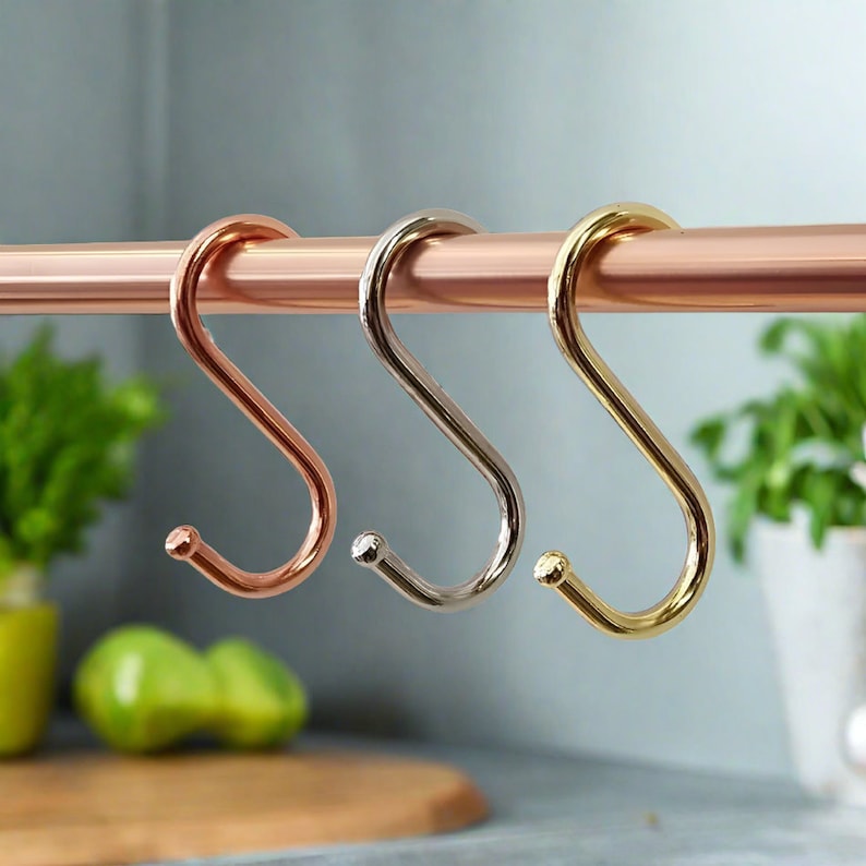 Three colourful utensil S-hooks hanging on a metal rod.
