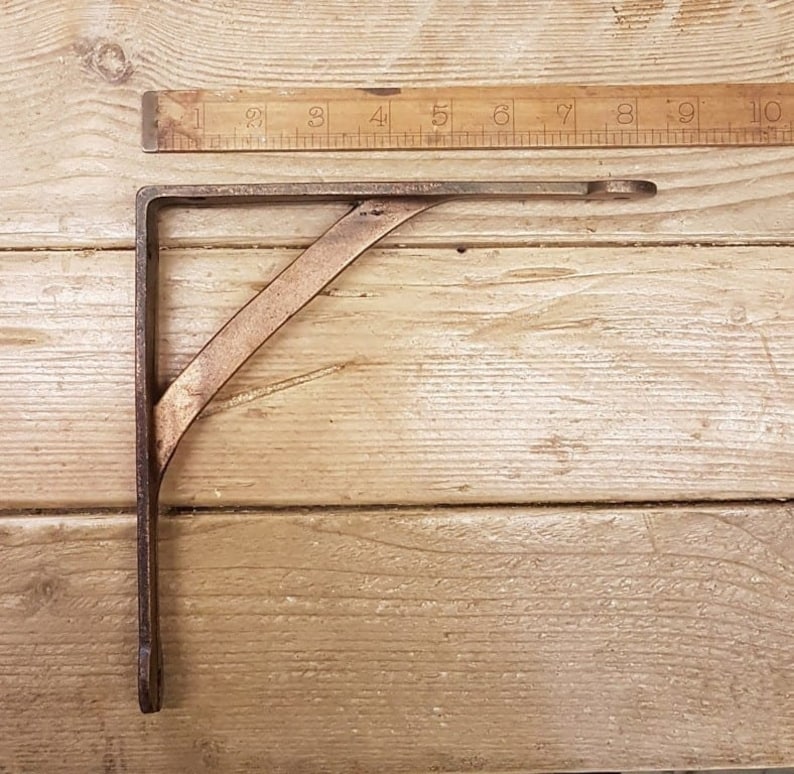Antique copper finish cast iron wall support on wooden surface