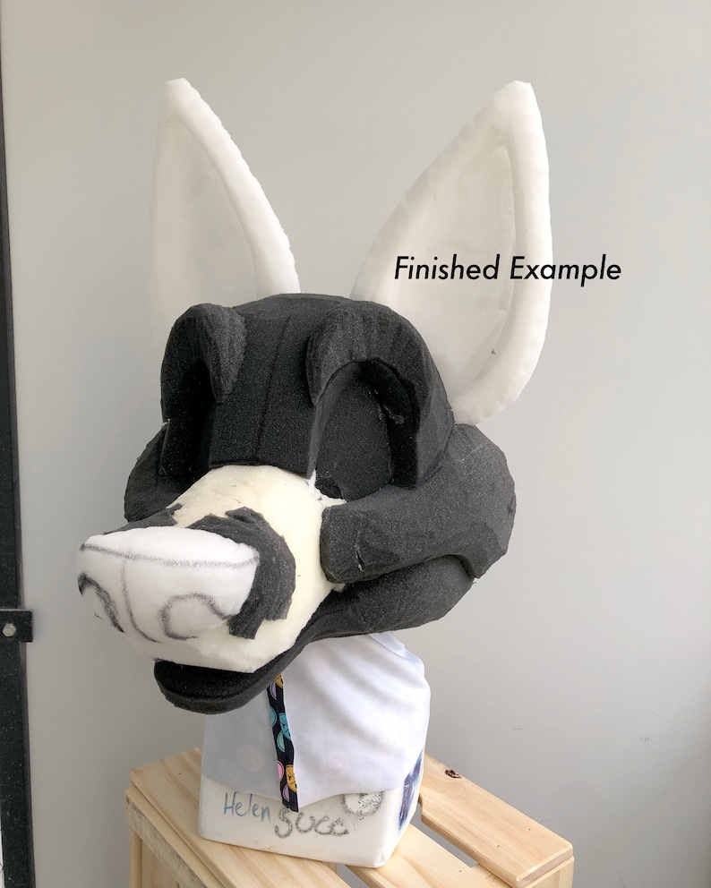May include: A white foam base for a furry costume head, with black foam detailing and white foam ears. The base is on a wooden stand and the text "Finished Example" is visible in the image.