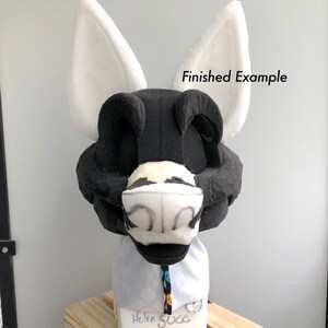 May include: A black and white fursuit head with white ears. The head is made of foam and is on a stand. The text "Finished Example" is visible in the image.