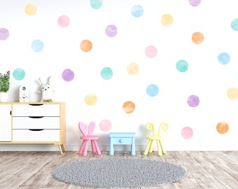 Puede incluir: Una pared blanca con pegatinas de pared de lunares de colores en tonos de azul, morado, naranja y amarillo. Hay dos sillas pequeñas y una mesa pequeña frente a la pared.