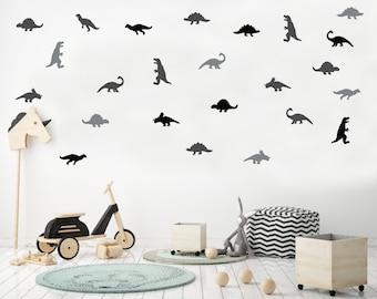 May include: A collection of black and grey dinosaur wall decals arranged in a scattered pattern. The set includes various species such as triceratops, stegosaurus, and tyrannosaurus rex silhouettes, providing a decorative theme for a room.