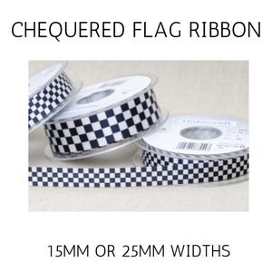 May include: Three spools of ribbon featuring a black and white chequered flag pattern. The text CHEQUERED FLAG RIBBON and 15MM OR 25MM WIDTHS is visible. The ribbon is wound onto clear plastic reels with white labels containing barcodes and brand text.