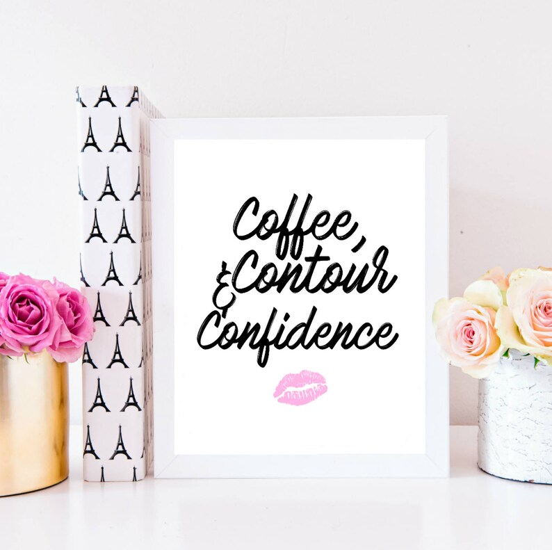 May include: White framed print with black text that reads "Coffee, Contour & Confidence" with a pink lipstick kiss mark below the text.