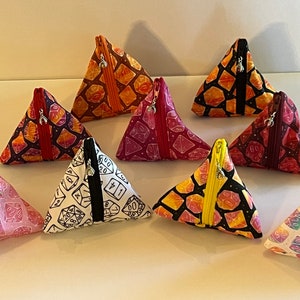 May include: Nine triangular zippered pouches with different dice patterns. The pouches are made of fabric and have a variety of colors, including red, pink, yellow, black, and white.