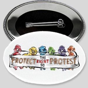 May include: A white oval button with a metal backing. The button features a colorful illustration of poodle-like figures holding a banner that reads "Protect the Right to Protest." The text "Poodle Protest Equality Button" is below.