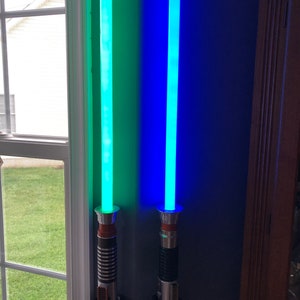May include: Two light sabers mounted on a wall, one is green and the other is blue.