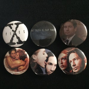May include: Six round button pins featuring characters and imagery from the television show The X-Files. The pins feature the show's logo, the text "The Truth is Out There", and images of the main characters, Mulder and Scully.