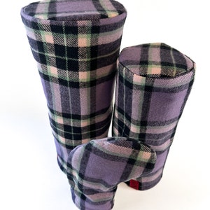 May include: Set of three golf club headcovers in a plaid pattern with purple, pink, black and green colours.