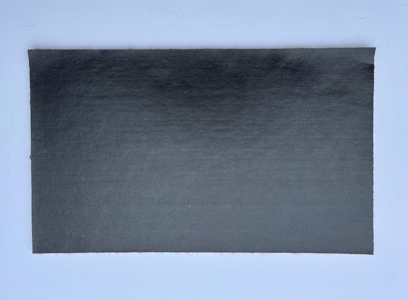 May include: A black sheet of paper with a slightly textured surface.