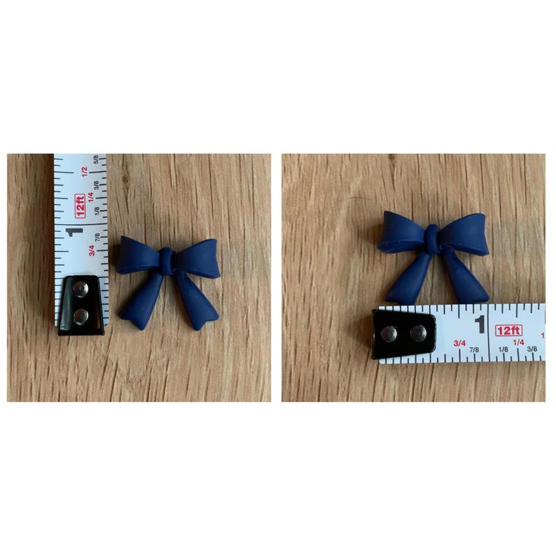 Puede incluir: Dos lazos de tela azul marino con acabado satinado. Los lazos miden aproximadamente 2,5 cm de ancho y se muestran junto a una regla para referencia de tama&ntilde;o.