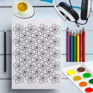 May include: A white sheet of paper with a black floral pattern, surrounded by colored pencils, a watercolor palette, a cup of coffee, a pencil, and headphones. The floral design is a repeating pattern of simple, five-petal flowers.