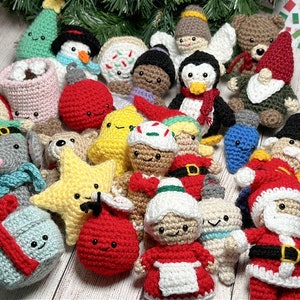 May include: A collection of crocheted Christmas ornaments, including a snowman, a penguin, a gingerbread man, a Santa Claus, a star, a stocking, a mug, and a Christmas tree. The ornaments are all handmade and feature bright colors and festive designs.