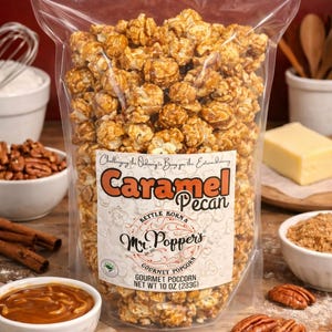 May include: A clear plastic bag filled with caramel pecan popcorn. The label reads: Challenging the Ordinary to Bring you the Extraordinary, Caramel Pecan, Kettle Korn & Mr. Popper's Gourmet Popcorn, Est 2017, Gourmet Popcorn, Net Wt 10 oz (283g).
