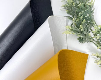 May include: Three sheets of faux leather in black, white, and mustard yellow. The sheets are folded and arranged in a triangular shape.