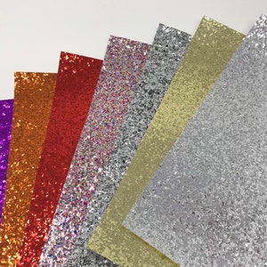 May include: Assortment of glitter paper sheets in various colors, including purple, orange, red, silver, and gold. The sheets are arranged in a fan shape, with the silver sheet at the bottom.