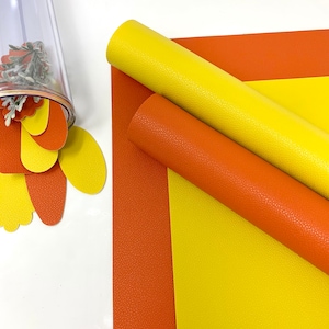 May include: Two rolls of faux leather in yellow and orange. The leather has a textured surface.
