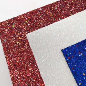 May include: Three sheets of glitter fabric in red, white, and blue. The red glitter fabric has a fine texture and is covered in small, colorful glitter. The white glitter fabric has a slightly coarser texture and is covered in white glitter. The blue glitter fabric has a fine texture and is covered in blue glitter with small red and white glitter accents.