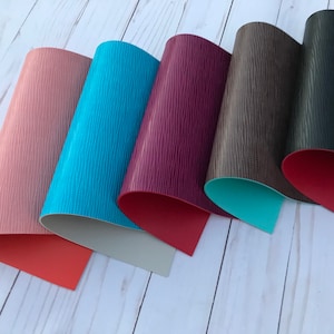 May include: Five sheets of faux leather in different colors, including pink, turquoise, burgundy, brown, and black. Each sheet has a textured surface and a contrasting colored backing.