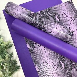May include: Two sheets of faux leather, one purple and one with a snakeskin pattern in shades of light purple and black.